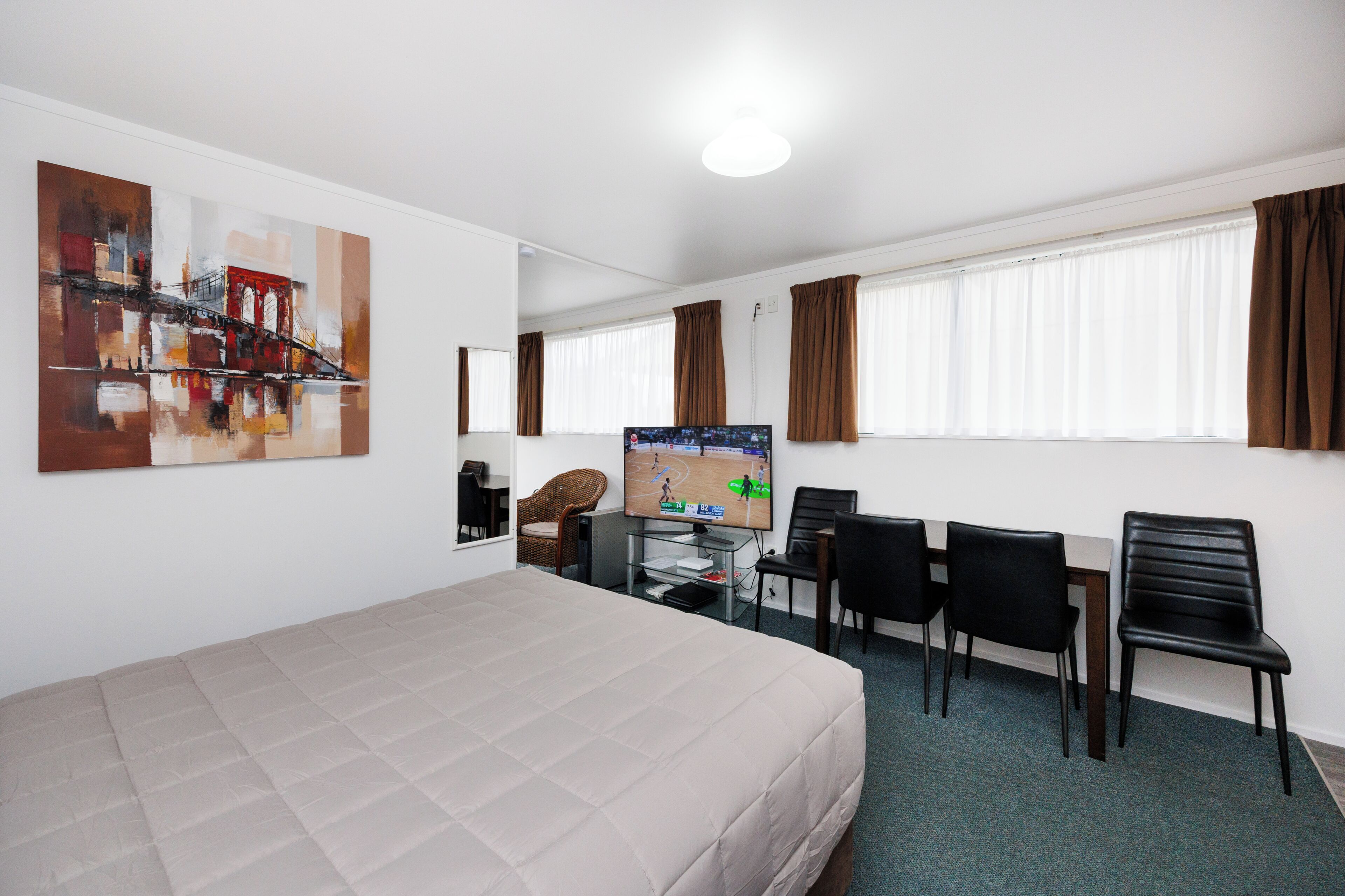 Habitación de hotel con cama, escritorio, computadora, silla y televisión.