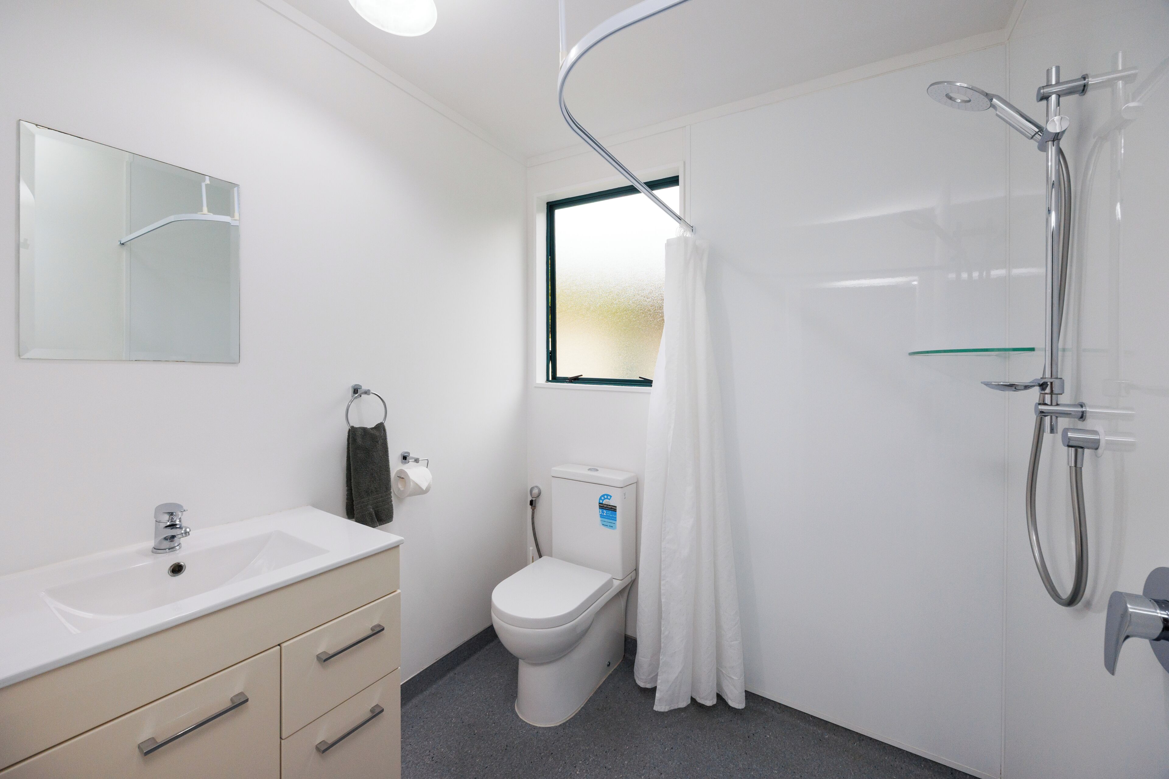 Un baño moderno con lavamanos, inodoro y ducha blancos.