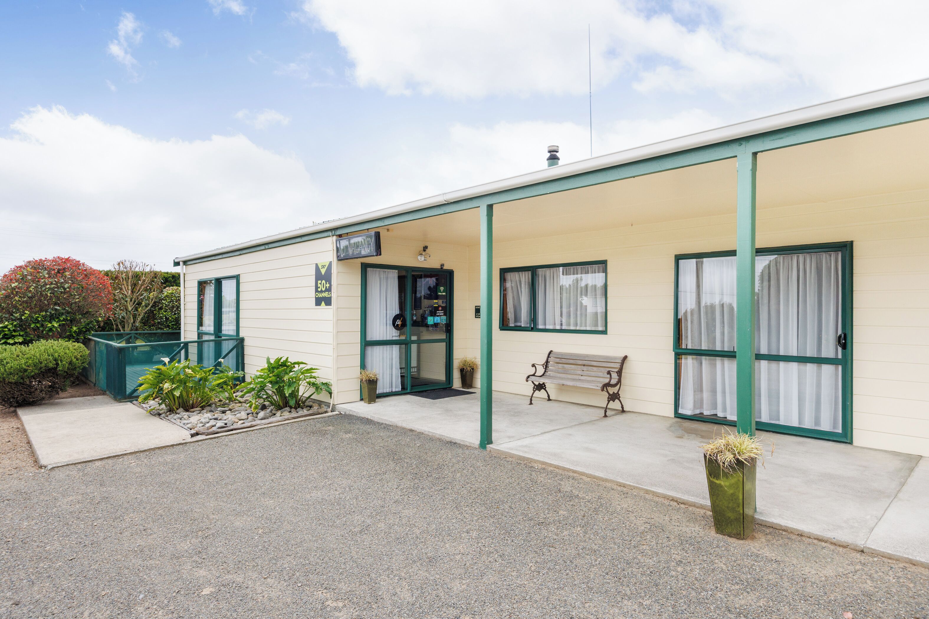 A building with a covered porch, a bench, and a door marked '50+ Dine In.'