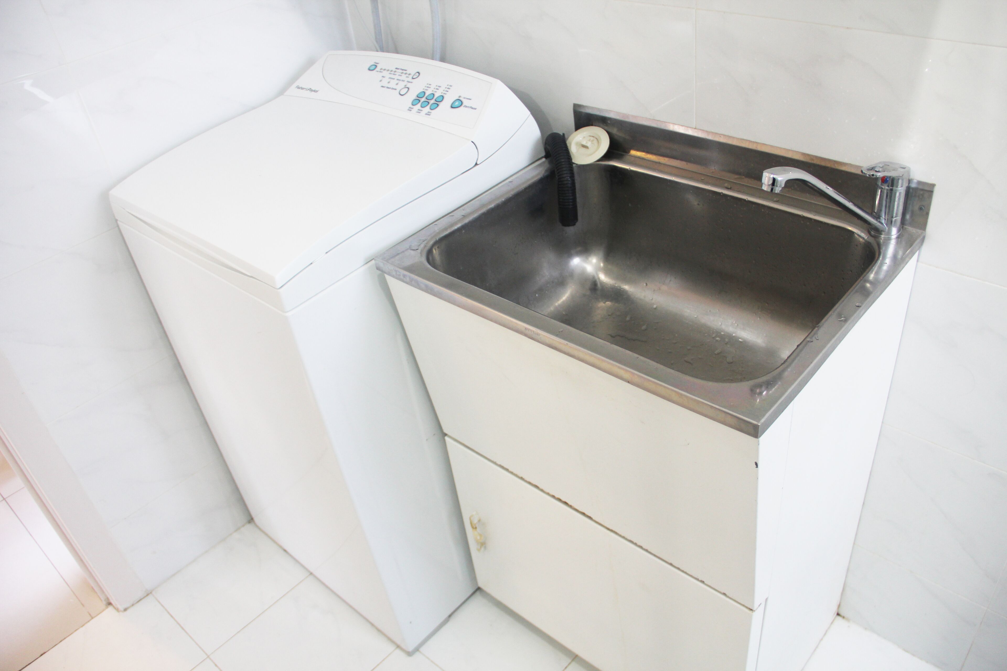 Una cucina compatta con lavatrice e lavello in acciaio inossidabile.