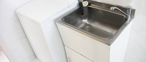 Una cucina compatta con lavatrice e lavello in acciaio inossidabile.