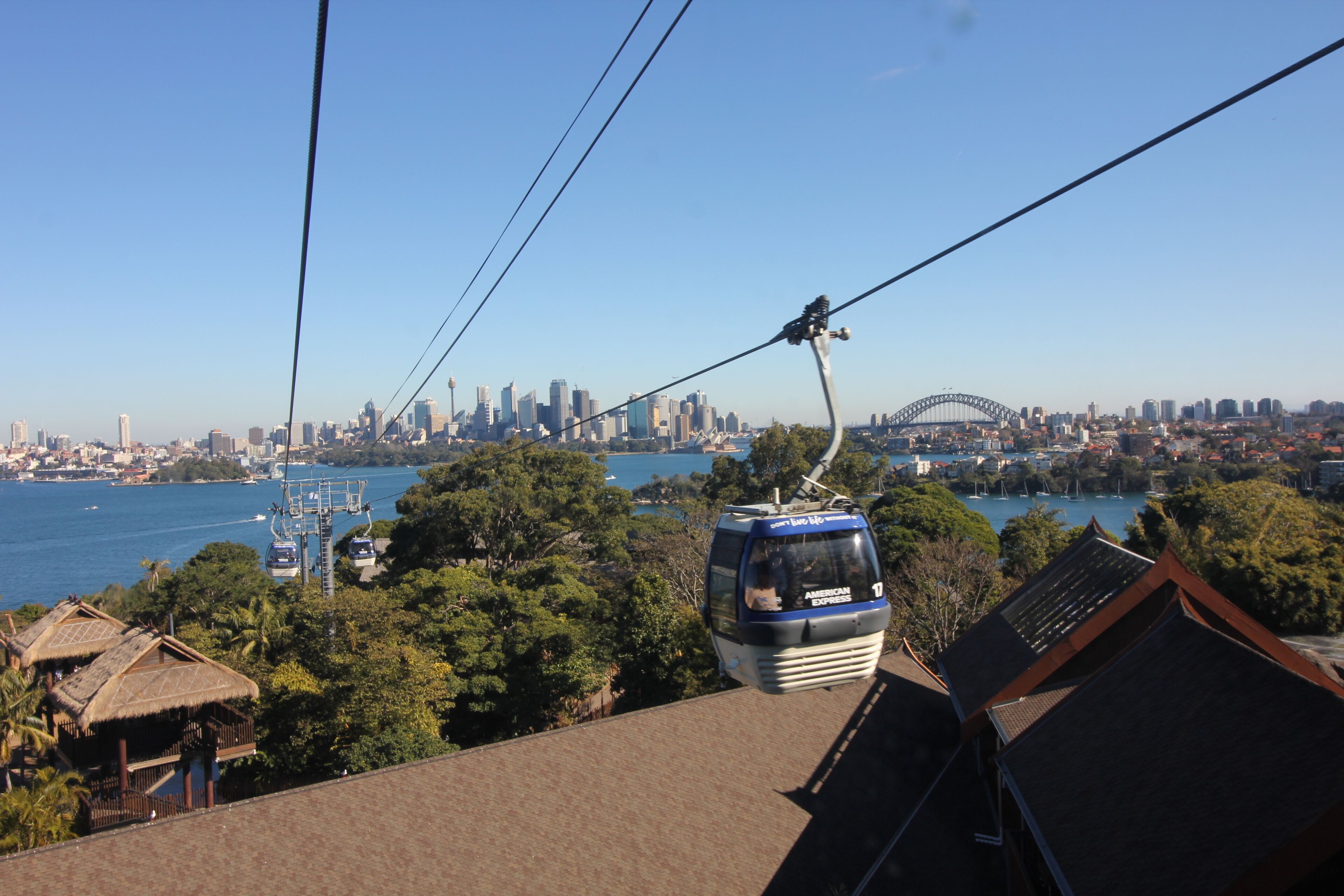 A cable car with a city skyline in the background, including a prominent bridge.