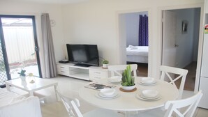 Ein Hotelzimmer mit Essbereich, Fernseher, Bett und einem durchgegangenen Tür erkennbaren Badezimmer.