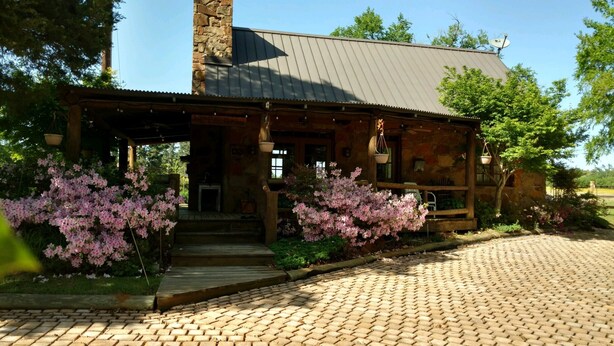 A rustic stone building with a covered porch and brick pathway.
