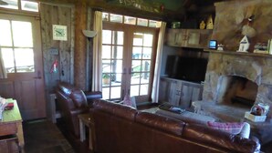 A cozy living room with a leather sofa, a stone fireplace, and a television.
