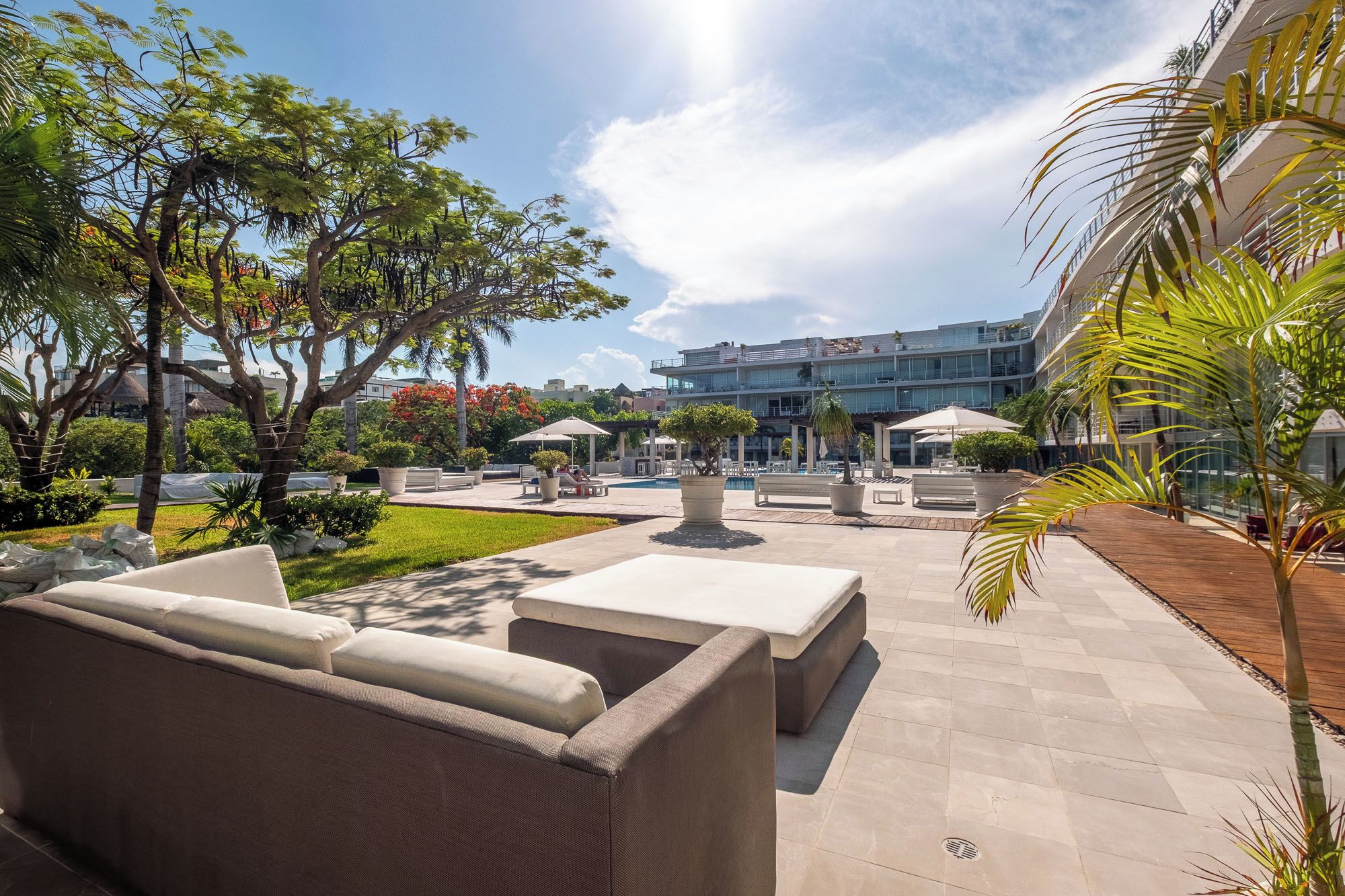 A courtyard with outdoor seating, a pool, and a modern building in the background.