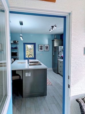 Una cocina con una isla central, microondas y refrigerador.