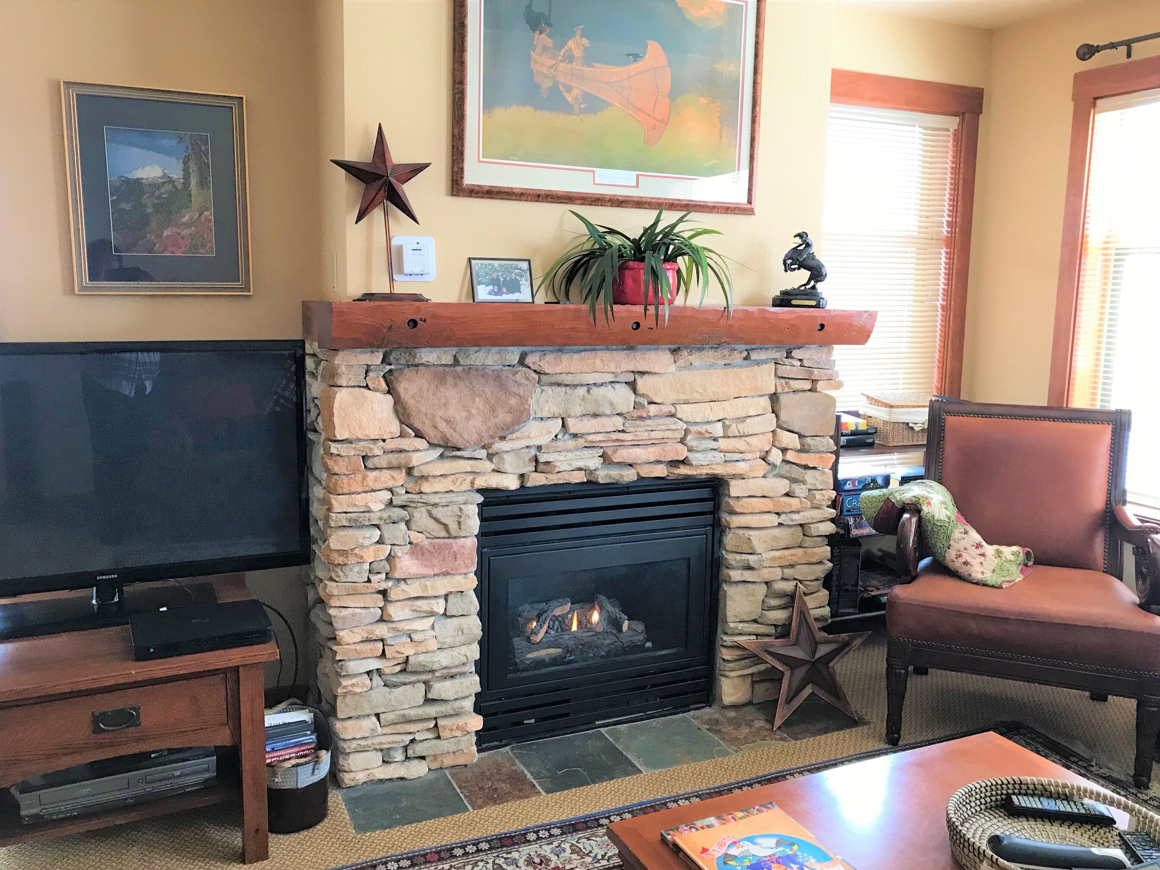 A living room with a stone fireplace, a flat-screen TV, and a comfortable seating area.