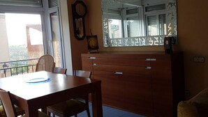A dining area with a wooden table and chairs, a large mirror, and a clock on the wall.