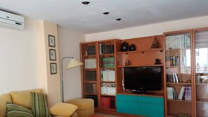 A living room with a sofa, a coffee table, a TV, and a bookshelf.