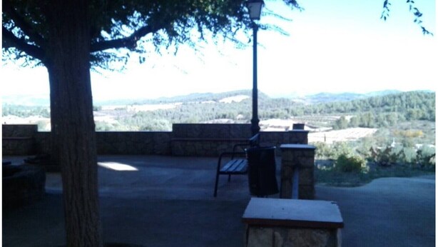 An outdoor patio area with a stone bench, a trash can, and a table.