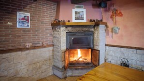 A cozy room with a stone fireplace, a brick wall, and a wooden table. - Casa Melchor for 9 people (Castejón)