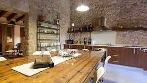 A rustic kitchen with stone walls, wooden furniture, and modern appliances.