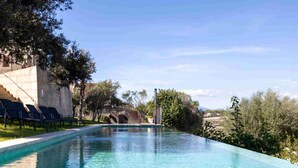 A clear swimming pool with lounge chairs and a stone building in the background.