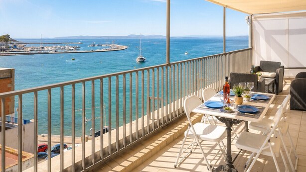 Een balkon met uitzicht op zee, een gedekte tafel en een stoel.