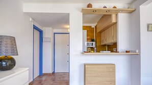 Een hal met een keukenhoek, een klein kastje en een decoratieve vaas.