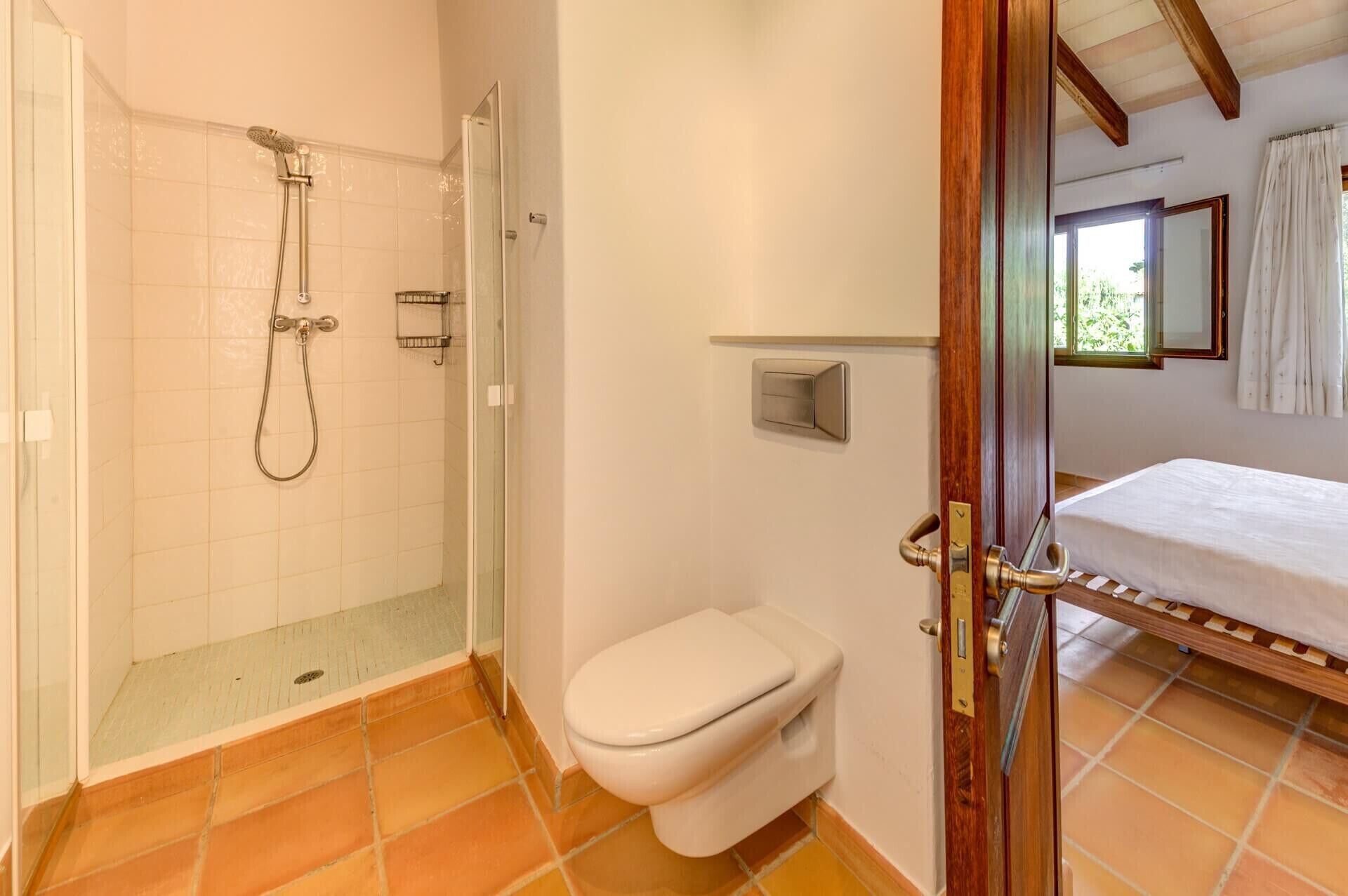 Une salle de bain avec une douche à parois de verre, des toilettes et un lit avec une tête de lit en bois.