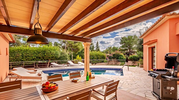 Un espacio al aire libre cubierto con piscina, sillas de descanso, una mesa de comedor con frutero y una parrilla.