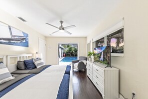 A bedroom with a bed, a ceiling fan, a TV, a dresser, and a view of a swimming pool. - Spacious WATERFRONT villa, heated salt water pool, very central, beach 5 min (Oakland Park)