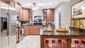 A modern kitchen with wooden cabinets, stainless steel appliances, and a central island with glassware. - Spacious WATERFRONT villa, heated salt water pool, very central, beach 5 min (Oakland Park)