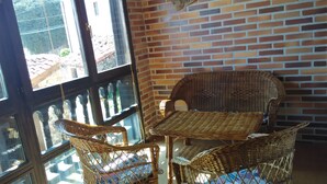 A wicker table and chairs set against a brick wall with a window in the background.