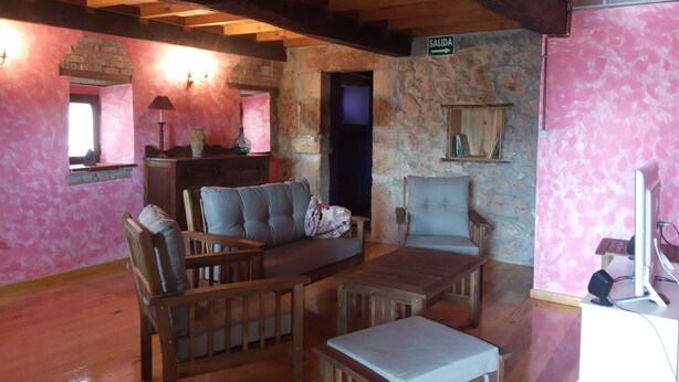 A cozy room with wooden furniture, a stone wall, and a sign indicating an exit.