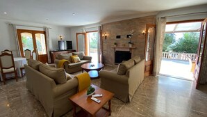 A spacious living room with a fireplace, comfortable seating, and a television. - Cottage `Es Garballó`. (Son Servera)
