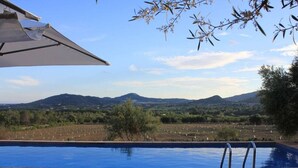 A swimming pool with lounge chairs and a view of the countryside. - Cottage `Es Garballó`. (Son Servera)