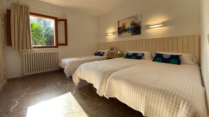 A bedroom with two beds, a window with curtains, a radiator, and a painting on the wall. - Cottage `Es Garballó`. (Son Servera)