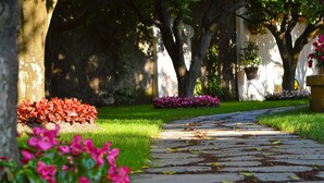 Un sendero de piedra que atraviesa un jardín con árboles y plantas en flor.