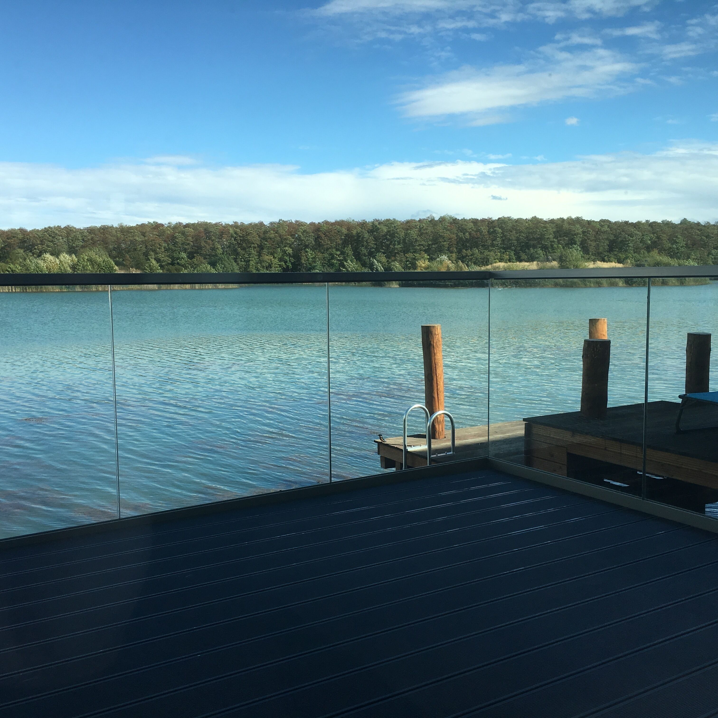 A deck with a view of a calm lake and a forested shoreline.