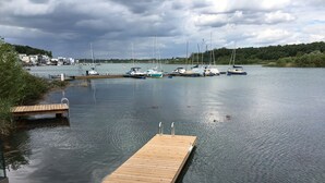Un muelle de madera se adentra en aguas tranquilas, con barcos amarrados al fondo.