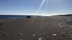 Une plage de galets avec un grand rocher au milieu.