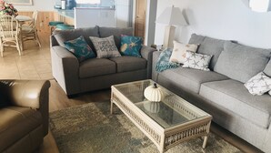 A living room with two sofas, a coffee table, and a dining area with chairs and a table. - Lovely 4 Bedroom Ocean view house in West Beach (Oak Island)