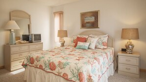 A bedroom with a bed, two bedside tables, a dresser, a television, and a painting on the wall. - Lovely 4 Bedroom Ocean view house in West Beach (Oak Island)