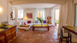 A spacious living area with a sofa set, a coffee table, and a kitchen area with a stove and sink. - Luxury And Peaceful Little Condo With Direct Access To The Beach (Zihuatanejo)