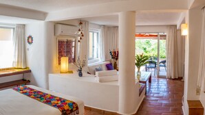 A hotel room with a bed, a sofa, a small table, and a view of the outdoors. - Luxury And Peaceful Little Condo With Direct Access To The Beach (Zihuatanejo)