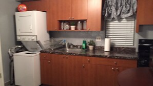 Cocina compacta con armarios de madera, horno integrado, lavamanos y una pequeña encimera.