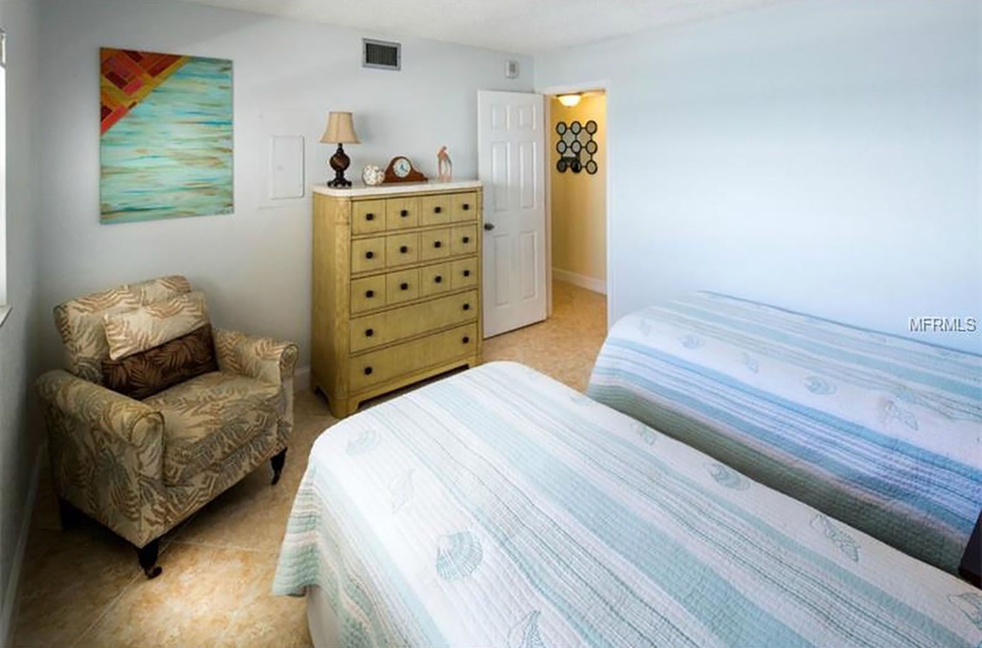 A bedroom with a bed, a chair, a dresser, and a door.