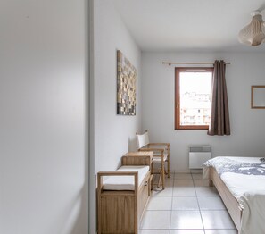 A compact bedroom with a bed, a desk, a chair, a radiator, and a window with curtains. - New apartment, near the ski resorts, due south, beautiful view of Risoul. (Guillestre)