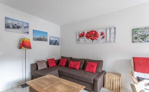 A living room with a sectional sofa, a wooden coffee table, and a red lamp. - New apartment, near the ski resorts, due south, beautiful view of Risoul. (Guillestre)