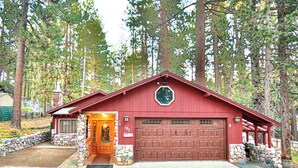 A red wooden cabin with a stone foundation, a garage, and a stone wall entrance. - Come Enjoy Tranquility In The Forest In Tahoe (Stateline)