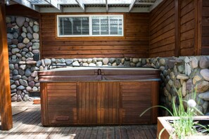 A hot tub with wooden walls and a stone wall. - Come Enjoy Tranquility In The Forest In Tahoe (Stateline)