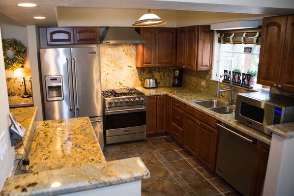 A modern kitchen with stainless steel appliances, granite countertops, and wooden cabinets. - Come Enjoy Tranquility In The Forest In Tahoe (Stateline)