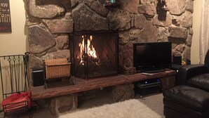 Una chimenea de piedra con televisor y altavoces, un espacio de estar cómodo y un ambiente acogedor.