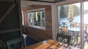A wooden deck with a table and chairs, a large window overlooking a body of water, and a sign reading "LAKE HOUSE". - Sandy Beach Oasis on Lake Ivanhoe (Wakefield)