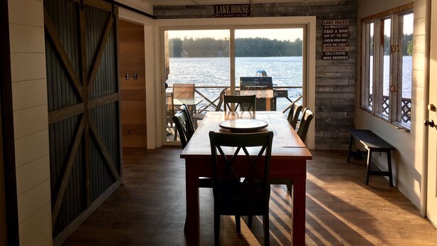 A dining area with a view of a lake, a grill, and a sign listing lake rules. - Sandy Beach Oasis on Lake Ivanhoe (Wakefield)