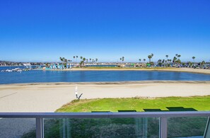 A coastal view with a sandy beach, palm trees, and a marina.