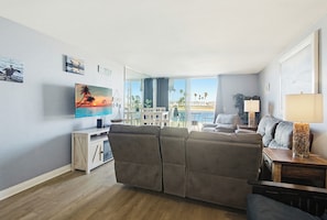Un salon avec un canapé, un téléviseur, une lampe et une vue sur l’extérieur.