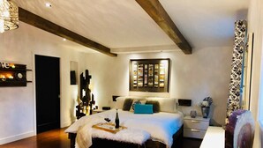 Une chambre moderne avec un grand lit, des tables de chevet, une lampe de chevet, un élément décoratif mural et une petite plante.